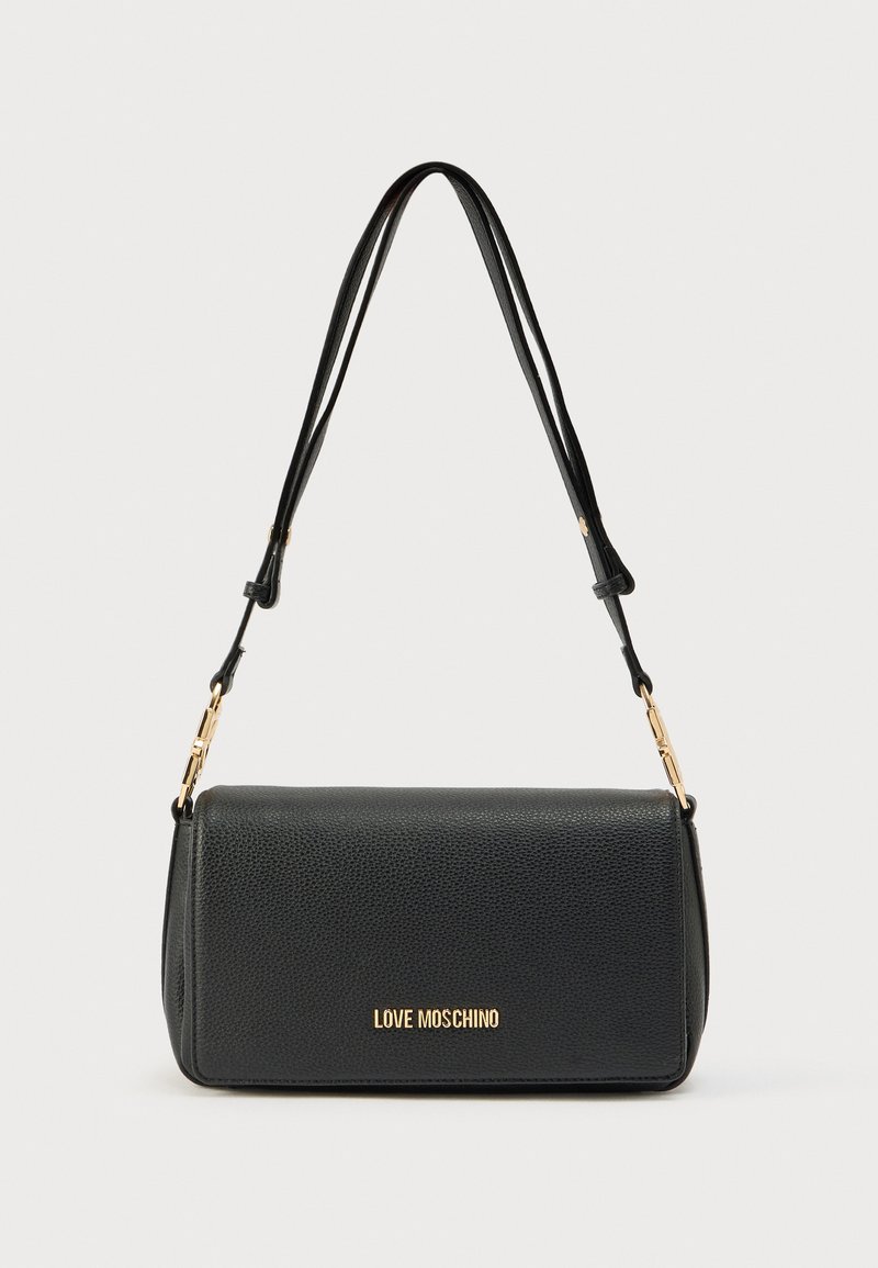 Μαύρη δερμάτινη τσάντα χειρός με υφή, μεταλλικά στοιχεία σε χρυσό τόνο και μακρύ ρυθμιζόμενο λουρί. Διαθέτει καπάκι και λογότυπο σε ανάγλυφη μορφή.