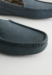 Plave mokasine s antilopom, zaobljenog vrha, minimalnim šavovima i mekim unutarnjim podstavljanjem. Glatka tekstura i nisko-profilni dizajn.