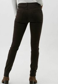 Jeans skinny marrones de denim, con cinco bolsillos y una cintura alta, acompañados de botas de tobillo de ante marrones.
