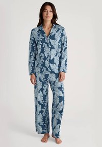 Modni komplet pižame z modrim cvetličnim vzorcem, ki vključuje dolg rokav s srajčnim zapiranjem na gumbe in ujemajoče hlače. Tkanina je mehka s gladko teksturo.