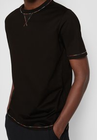 Svart kortärmad t-shirt i en mjuk tygkvalitet, med en färgglad detalj längs kragen och ärmarna, med en avslappnad passform.