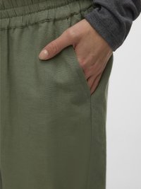 Helerohelised linased püksid elastse vöörihmaga, millel on küljetaskud. Käsi puhkab tasku serval, tuues esile peene tekstuuri.