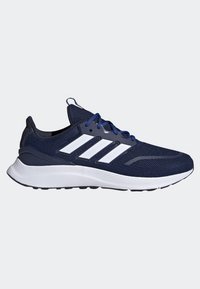 Baskets de sport bleu foncé avec semelle blanche, logo blanc à trois bandes sur le côté et lacets bleus sur fond gris uni.