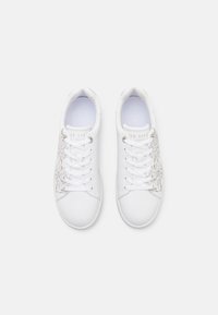 Zapatillas blancas de cuero suave con diseño de bordado floral en dorado metálico en un lado y cierre de cordones tradicional.