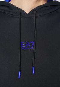 Svart huva tröja med lila logotyp och dragskoändar. Har en jämn textur och en enkel, modern design.