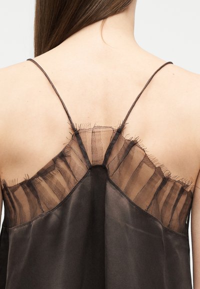 Πίσω όψη ενός ατόμου που φοράει ένα καφέ σκούρο σατέν καμηλό με διαφανή, βολάν λεπτομέρεια από δίχτυ και λεπτές ραντάκια στους ώμους.