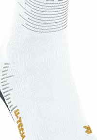 Calza sportiva bianca con motivo a strisce grigie e maglia testurata. Presenta dettagli neri e un logo ricamato dorato sul lato.