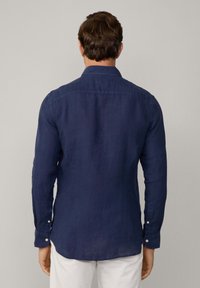 Camicia di lino blu navy a maniche lunghe con colletto button-down, caratterizzata da una superficie liscia e bottoni bianchi sui polsini. Visuale posteriore mostrata.