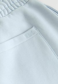 Tela azul claro con una textura suave, que presenta costuras fruncidas y una pequeña etiqueta en relieve en la parte posterior que dice "EDIT."