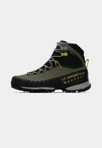 Scarponi da montagna in verde oliva e nero, dotati di Gore-Tex per l'impermeabilità, punta in gomma, suola robusta e accenti gialli.