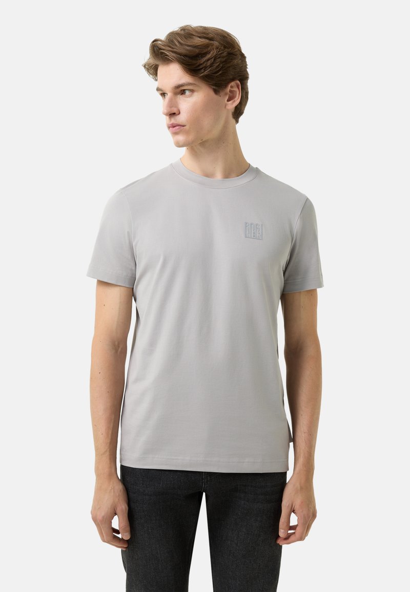 Grå T-shirt med korte ærmer i et glat stof med rund hals. Har et diskret logo på venstre bryst og et rent, minimalistisk design.