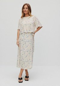 Blommig klänning och kort topp i ljusbeige tyg, med en lös passform, korta ärmar och delikata mönster av blå och rosa blommor.