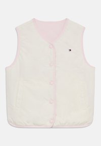 Krátka bezrukávová vesta v krémovej farbe s ružovým lemovaním, s gombíkovým zapínaním a dvoma bočnými vreckami. Diskrétny detail loga na prednej strane.
