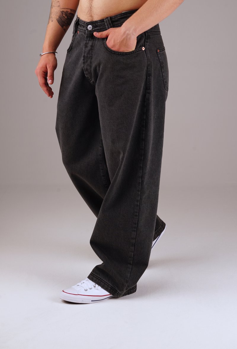Loose-fitting black denim jeans with a faded appearance, five-pocket design, metal button closure, and contrasting stitching details.