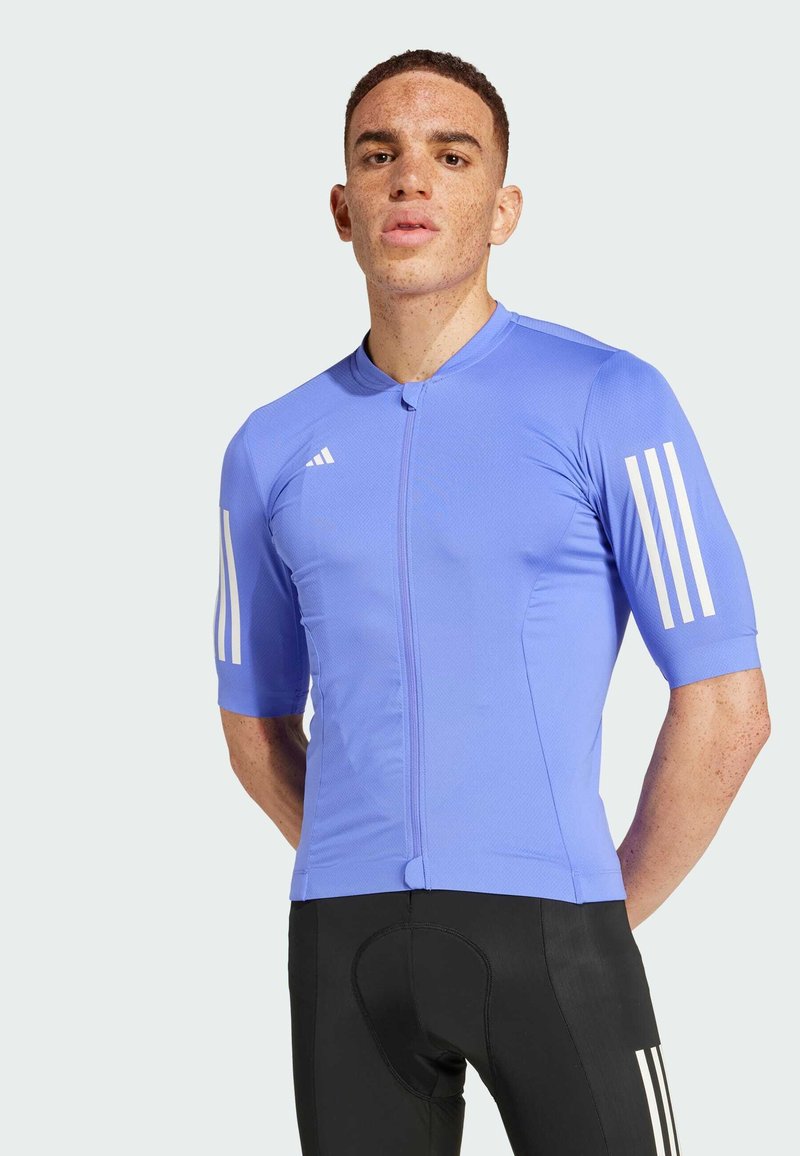 Pánský cyklistický dres s krátkým rukávem v světle modré barvě, vyrobený z texturovaného materiálu. Obsahuje zip na přední straně a tři bílé pruhy na rukávech.