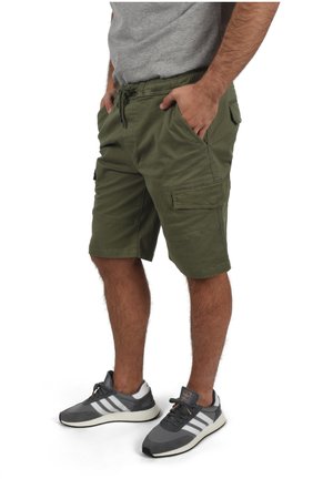 Olive green cargo shorts made of cotton, featuring side pockets and an elastic waistband with drawstring. Paired with gray athletic shoes.