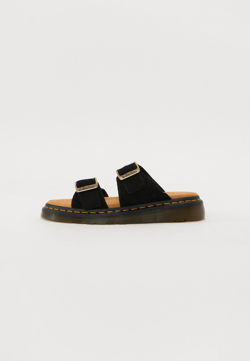 Black suede sandals feature two adjustable straps, a cushioned tan insole, and a thick rubber sole with yellow stitching accents.