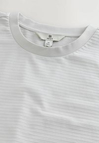 Gråstribet kortærmet t-shirt med rund hals. Fremstillet af blødt stof, med et mærke, der viser brandnavnet "NEXT" og størrelse "M."