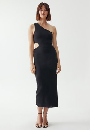 Black, one-shoulder midi dress featuring a side cutout, smooth texture, fitted silhouette, and straight hem. Accompanied by black strappy heels.