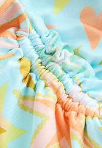 Jasná saténová látka s pružným nariasením obsahujúca pastelové hviezdy a srdcové vzory v modrej, oranžovej, žltej a zelenej farbe.