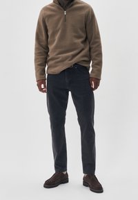 Pullover in pile beige con zip a tre quarti, jeans in denim scuro, scarpe in suede marrone scuro, vestibilità slim, tessuto testurizzato, design semplice.
