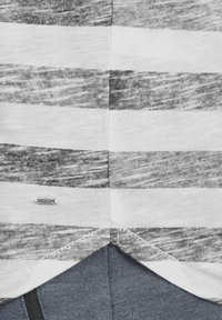 Stripete T-skjorte med grå og hvite horisontale striper, laget av mykt bomullsmateriale, med et merke som leser "SOLIDE" nær sømmen.