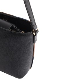 Černá kožená taška s texturou, se zipovou kapsou a zlatými kovovými prvky. Obsahuje tenký nastavitelný popruh a kontrastní barevné boční panely.