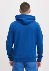 Felpa blu realizzata in tessuto morbido, con cappuccio, polsini e orlo a costine. Texture liscia senza motivi visibili o dettagli in metallo.