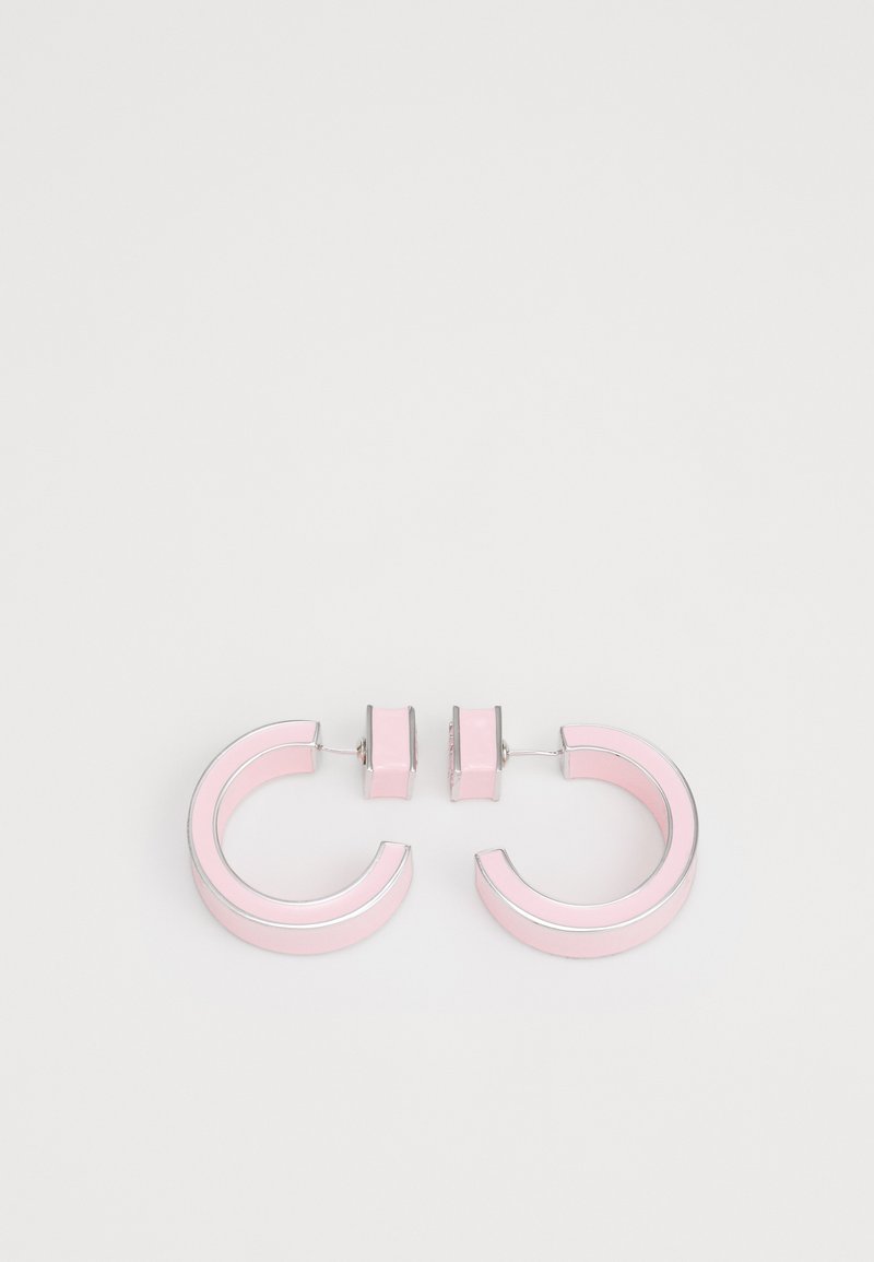 Boucles d'oreilles circulaires roses avec des accents en argent, présentant une finition brillante et un design en chunky, reliées par une petite pièce rose.
