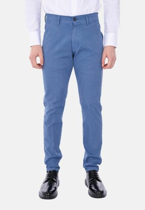 Chinos azzurri chiari in cotone, con un taglio slim, chiusura frontale a bottone e passanti per cintura, abbinati a scarpe eleganti nere.