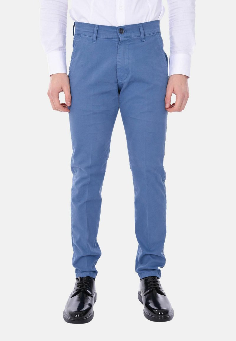 Chinos azzurri chiari in cotone, con un taglio slim, chiusura frontale a bottone e passanti per cintura, abbinati a scarpe eleganti nere.