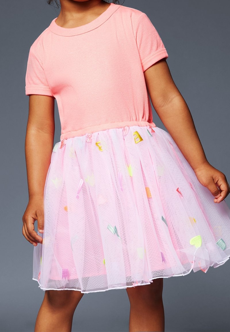 Robe en coton rose avec un haut à manches courtes et une jupe en tulle rose transparente à plusieurs couches, ornée d'appliqués colorés en forme de cœurs et d'étoiles.