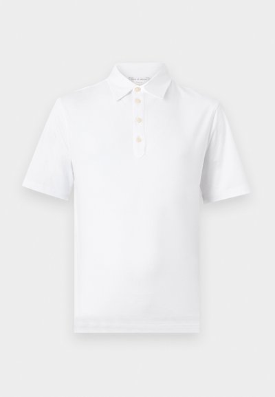 Λευκό πόλο με κοντά μανίκια, κλασικό γιακά και τέσσερα μπεζ κουμπιά στο πλάισιο, απεικονισμένο πάνω σε ανοιχτό φόντο.