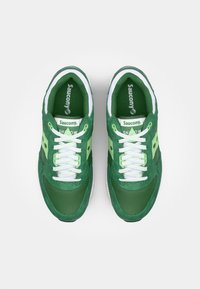 Grønne Saucony Shadow joggesko med overdel i mesh og semsket skinn, hvite snørebånd og lysegrønne detaljer; gummisåle med teksturert utforming.