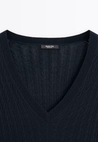 Marineblauer Strickpullover mit Zopfmuster, V-Ausschnitt und einem "Massimo Dutti" Markenschild, das am Kragen innen angenäht ist.