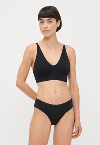 Zwart lingeriesetje met een naadloze V-hals bralette met brede banden en bijpassende high-waisted slipjes met een golvende rand.