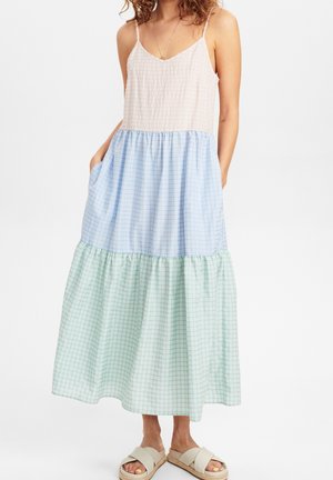 Maxikleid mit einem hellrosa Oberteil und einem mehrstufigen Rock in blau-grünen Karomustern. Hergestellt aus leichtem Stoff, mit verstellbaren Trägern und Taschen.