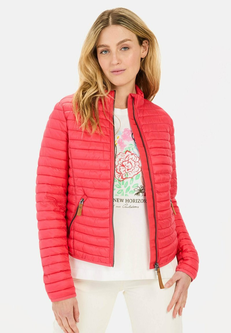Rote gesteppte Jacke mit Reißverschluss vorne und Seitentaschen. Verfügt über einen Stehkragen und eine weiche Textur. Getragen über einem weißen Grafikshirt.