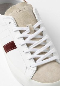 Hvide lædersneakers med beige suede-detaljer, burgunderrøde striber og hvide snørebånd. Har en tekstureret tåhætte og logo på tungen.