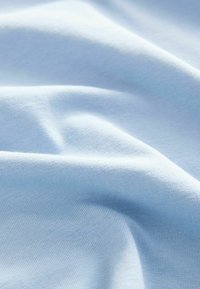 Světlá modrá bavlněná tkanina s hladkou strukturou, s jemným elastickým vlastnostmi a jemně žebrovanými vzory, položená v měkkých záhybech.