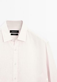 Light pink linen shirt with a standard collar, front button closure, and stitched detailing. Labels read "Massimo Dutti" and care information.