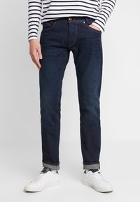 Mörkblå denimjeans med rak passform, som har en klassisk femficksdesign och subtila sömnadsdetaljer. Bärs med vita sneakers.