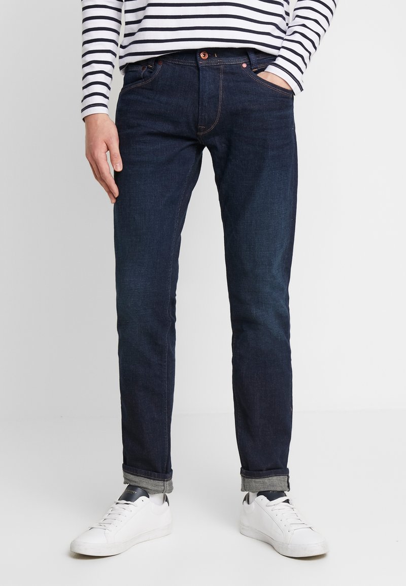 Mörkblå denimjeans med rak passform, som har en klassisk femficksdesign och subtila sömnadsdetaljer. Bärs med vita sneakers.