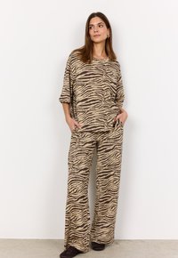 Loungewear-Set mit zebramuster in Tan und Braun, bestehend aus einem lockeren, kurzärmeligen Oberteil und weit geschnittenen Hosen mit Taschen. Weicher Stoff und lässige Passform.