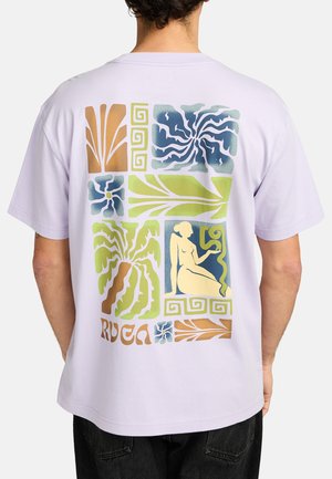 T-shirt lilas avec un imprimé graphique coloré au dos, comprenant des motifs abstraits, des motifs floraux et une figure assise.