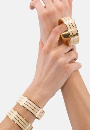 Bracelets de poignet en or, avec une surface lisse et des lignes gravées horizontales. Fini métallique poli, forme ronde et plate.