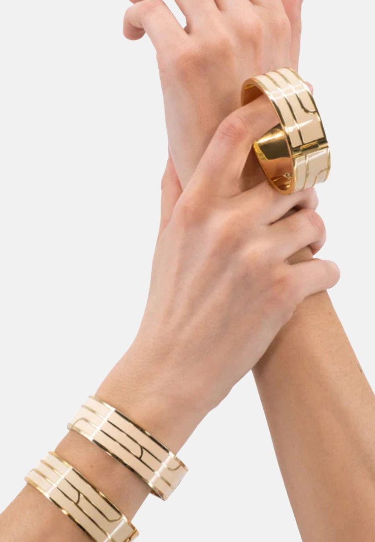 Bracelets de poignet en or, avec une surface lisse et des lignes gravées horizontales. Fini métallique poli, forme ronde et plate.