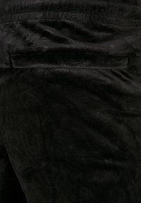 Sort tekstureret stof med et diskret præget mønster. Materialet virker blødt med en let glans, velegnet til beklædning.