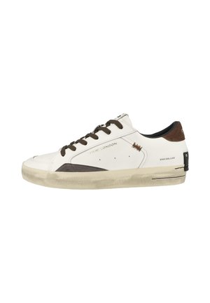 Sneaker bianca bassa con lacci marroni, inserti in camoscio e suola beige leggermente usurata, mostrata di profilo su sfondo bianco.