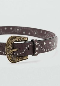 Rjav usnjen pas z okrasno zlatim zaponko, okrašen z reliefnimi vzorci in srebrnimi zakovicami vzdolž celotne dolžine. Gladek občutek, klasičen dizajn.